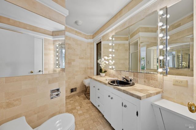 a bathroom with a granite countertop sink a toilet a mirror and shower