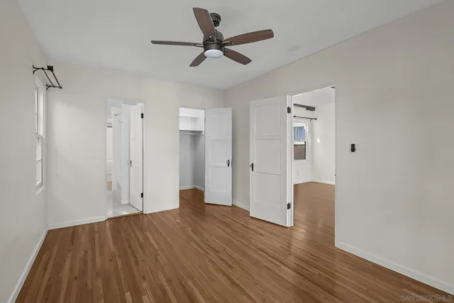 a view of empty room with wooden floor and ceiling fan