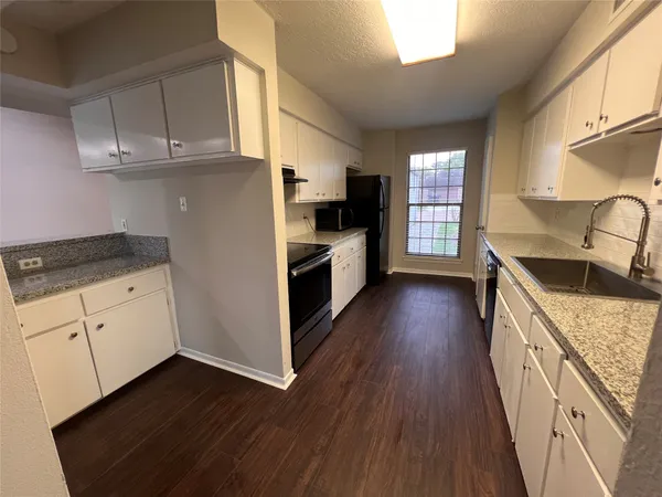 a kitchen with granite countertop a stove a sink dishwasher and a refrigerator with wooden floor