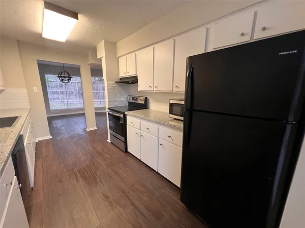 a kitchen with a refrigerator a stove top oven and wooden floors