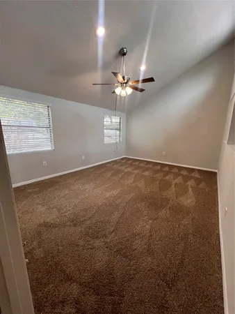 an empty room with a chandelier fan and windows