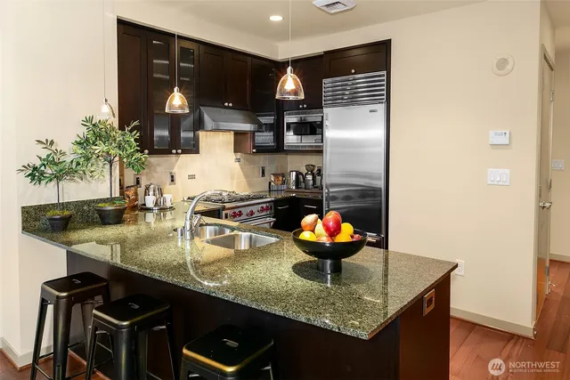 a kitchen with stainless steel appliances granite countertop a sink and a refrigerator