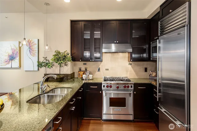 a kitchen with kitchen island granite countertop a sink stainless steel appliances and cabinets