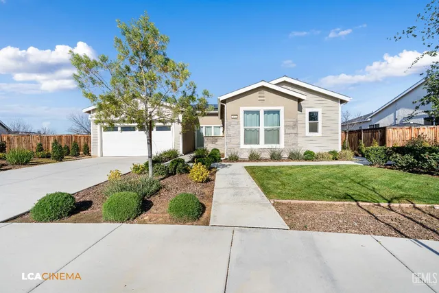a front view of a house with a yard and potted plants