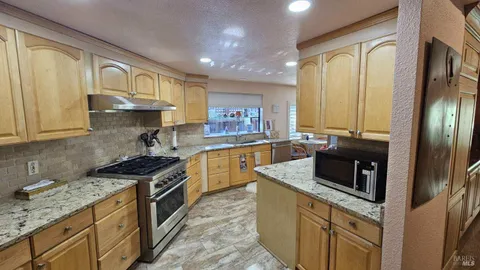 a kitchen with granite countertop stainless steel appliances a stove sink and refrigerator