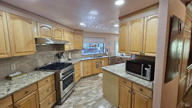 a kitchen with granite countertop stainless steel appliances a stove sink and refrigerator