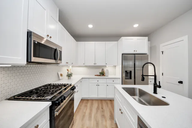 a kitchen with granite countertop a sink a stove and refrigerator