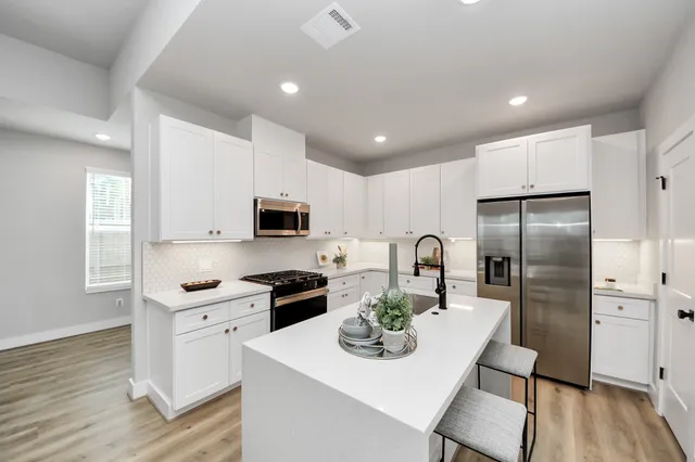 a kitchen with stainless steel appliances granite countertop a sink a stove a refrigerator cabinets and wooden floor