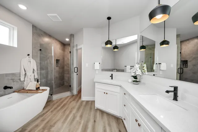 a bathroom with a double vanity sink a mirror a bathtub and shower