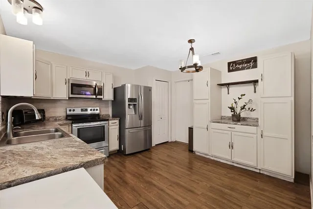 a kitchen with stainless steel appliances granite countertop a stove a sink dishwasher and a refrigerator with wooden floor