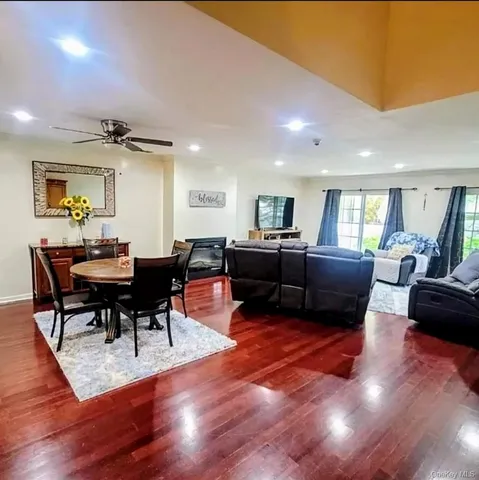 a living room with furniture a fireplace and a dining table with wooden floor