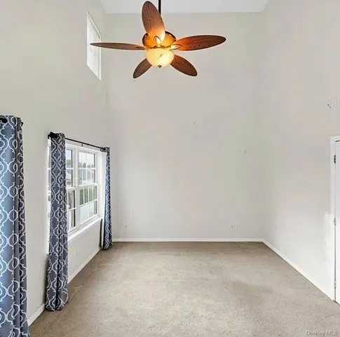 an empty room with chandelier fan and windows