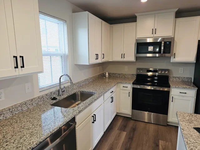 a kitchen with granite countertop a sink a stove and cabinets