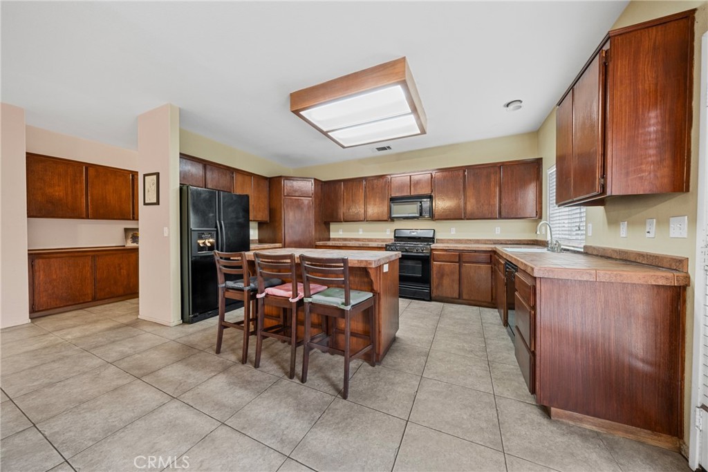1727 Miranda Lane Beaumont, CA 92223 - Photo 3 of 47 a kitchen with stainless steel appliances kitchen island granite countertop a refrigerator and a stove top oven
