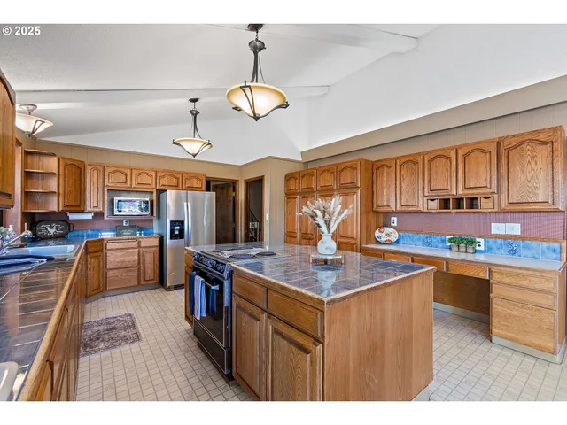 a kitchen with stainless steel appliances granite countertop a sink a stove and a wooden floors