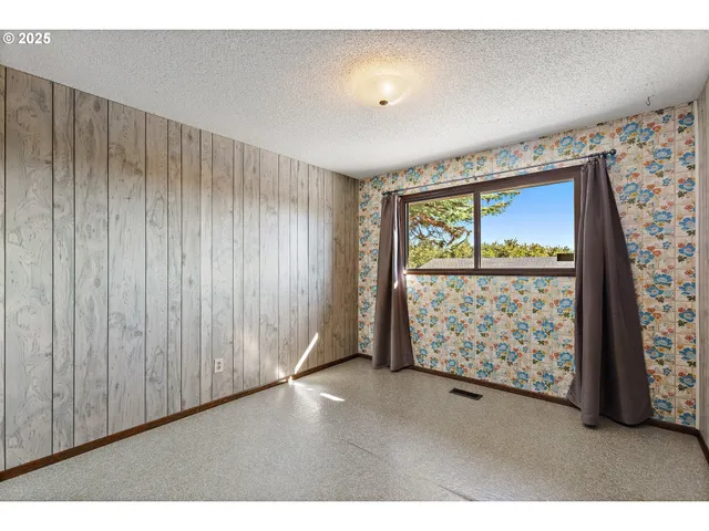 a view of an empty room with windows & cabinet