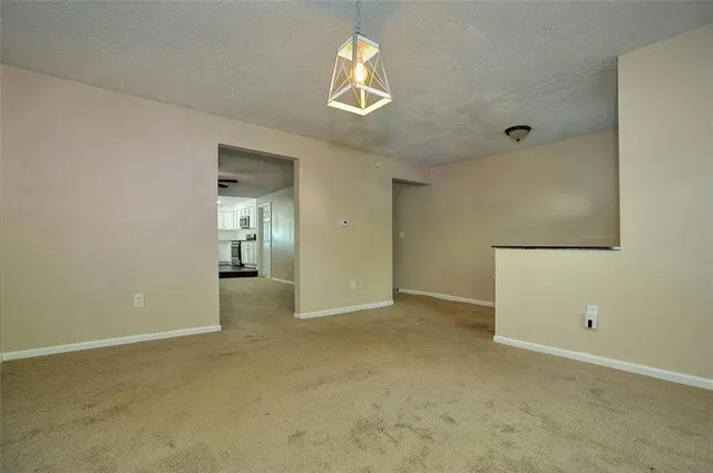 an empty room with chandelier fan and windows