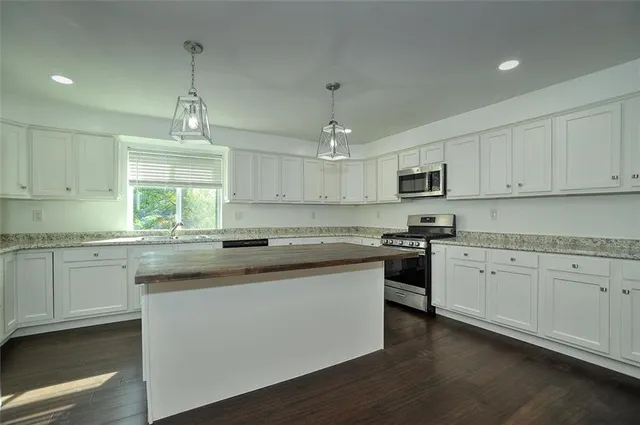 a kitchen with granite countertop white cabinets and white stainless steel appliances
