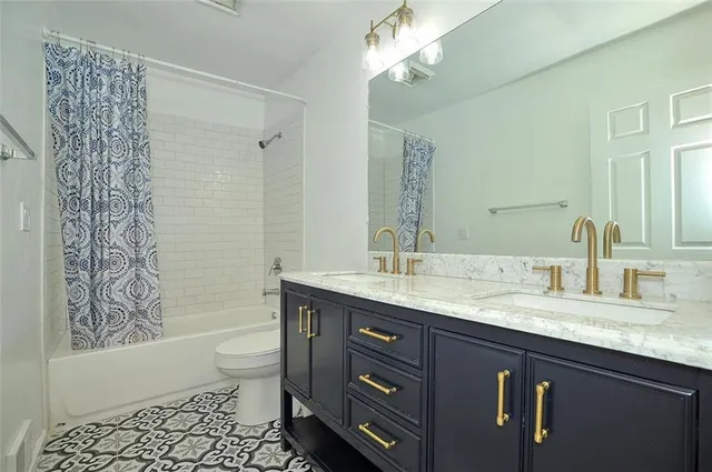 a bathroom with a granite countertop sink a toilet a mirror a bathtub and shower