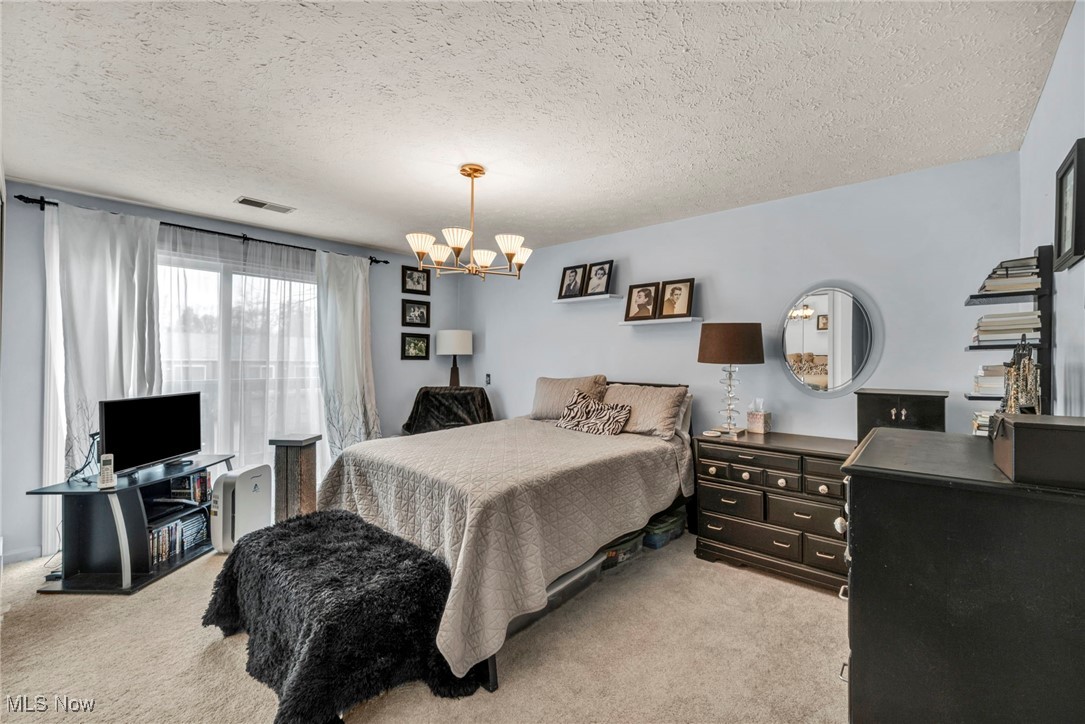 4750 Oak Point Road, Unit 304 Lorain, OH 44053 - Photo 22 of 29 Bedroom featuring light colored carpet, a textured ceiling, and a chandelier