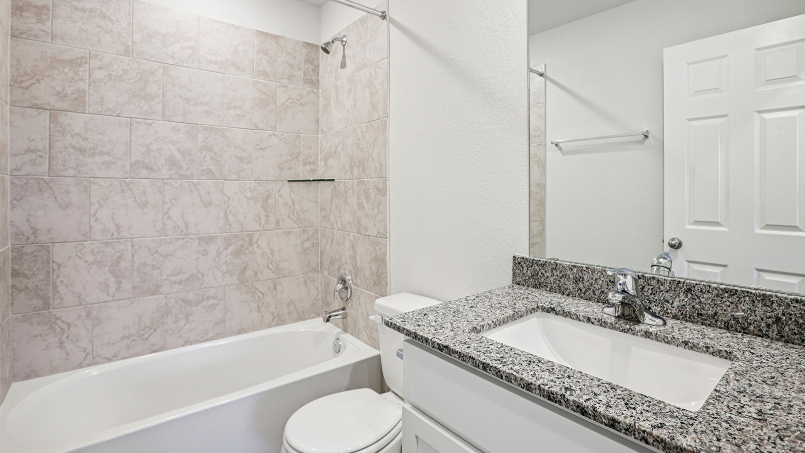 148 Wyatt Way Jarrell, TX 76537 - Photo 31 of 33 Bathroom featuring a white bathtub, beige subway tile surround, granite countertop, undermount sink, and chrome fixtures