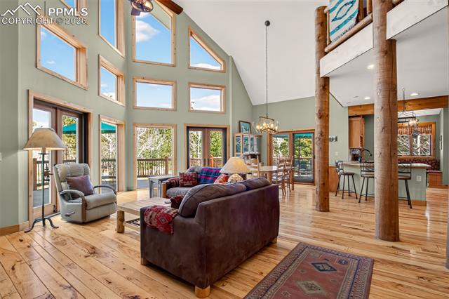 255 Summit Road Manitou Springs, CO 80829 - Photo 3 of 48 Open concept great room with vaulted ceilings, a walk out to wrap around deck, a wall of windows for plenty of natural light, knotty pecan flooring and a river rock gas fireplace