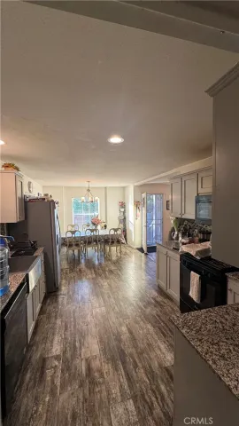 a kitchen with stainless steel appliances granite countertop a stove top oven a sink dishwasher a dining table and chairs with wooden floor