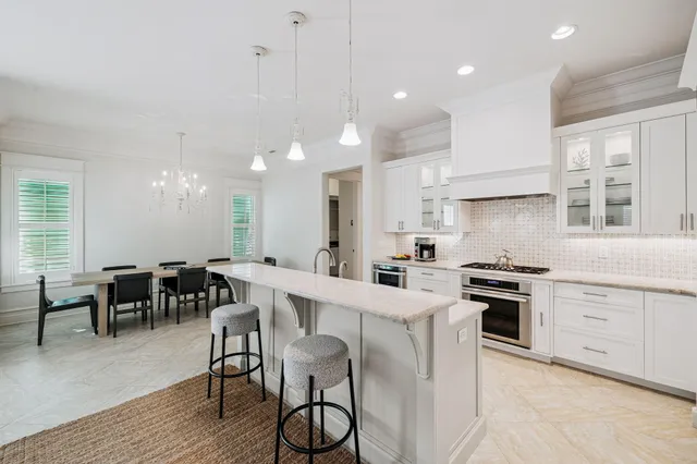 a kitchen with stainless steel appliances granite countertop a stove top oven a sink dishwasher a dining table and chairs with wooden floor