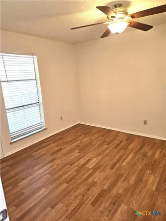 an empty room with wooden floor and fan
