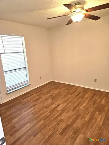 an empty room with wooden floor and fan