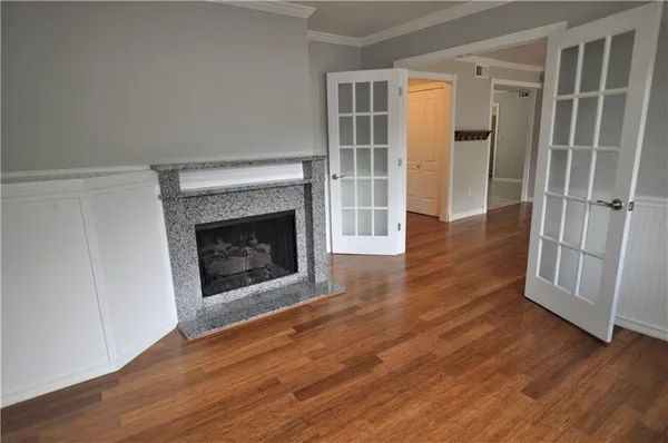 an empty room with wooden floor fireplace and windows