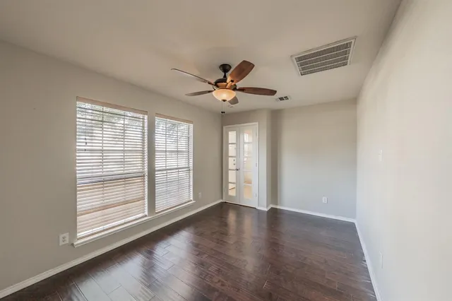 a view of an empty room with wooden floor and a window