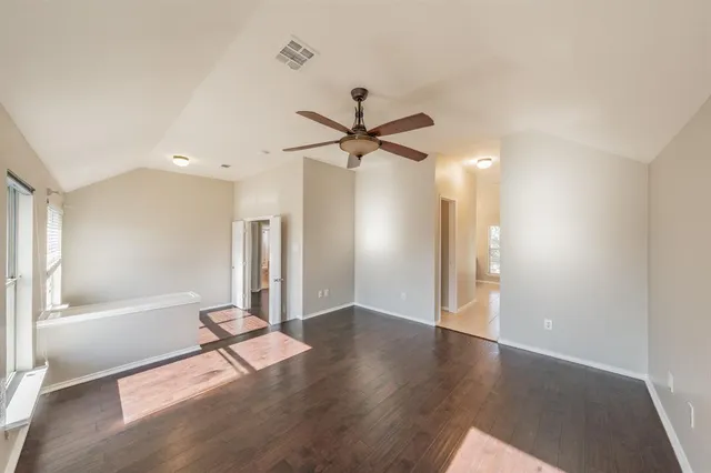 an empty room with wooden floor and a ceiling fan