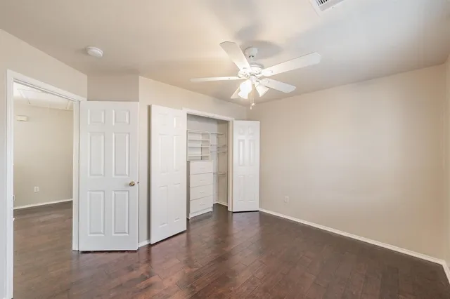 an empty room with wooden floor and ceiling fan
