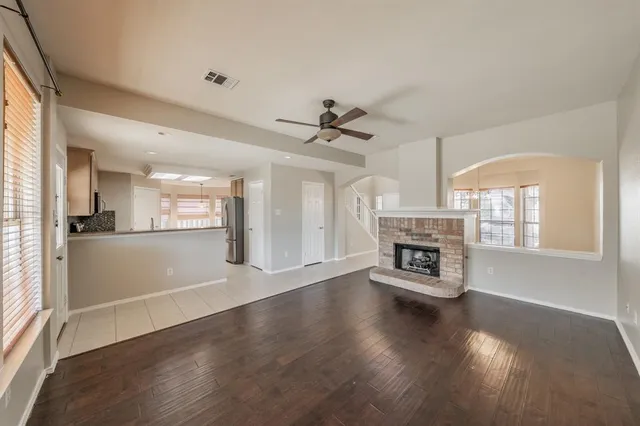 an empty space with wooden floor a fireplace and windows