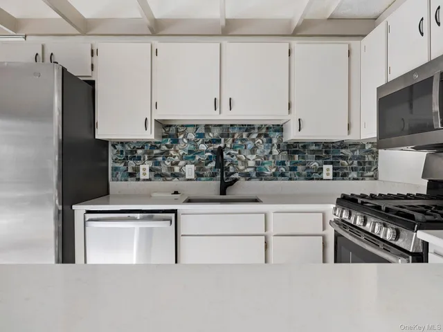 a kitchen with stainless steel appliances white cabinets and a stove top oven