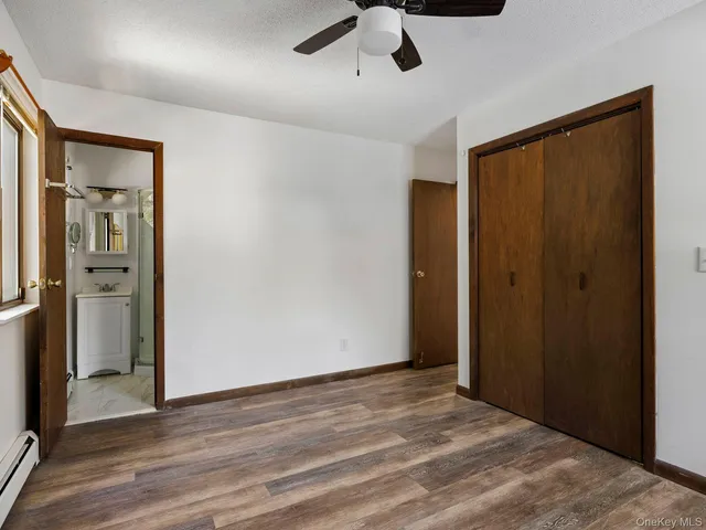 a view of an empty room with wooden floor and a ceiling fan