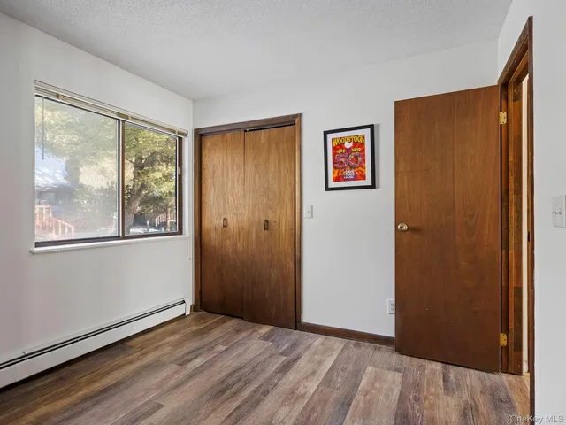 a view of an empty room with window and wooden floor