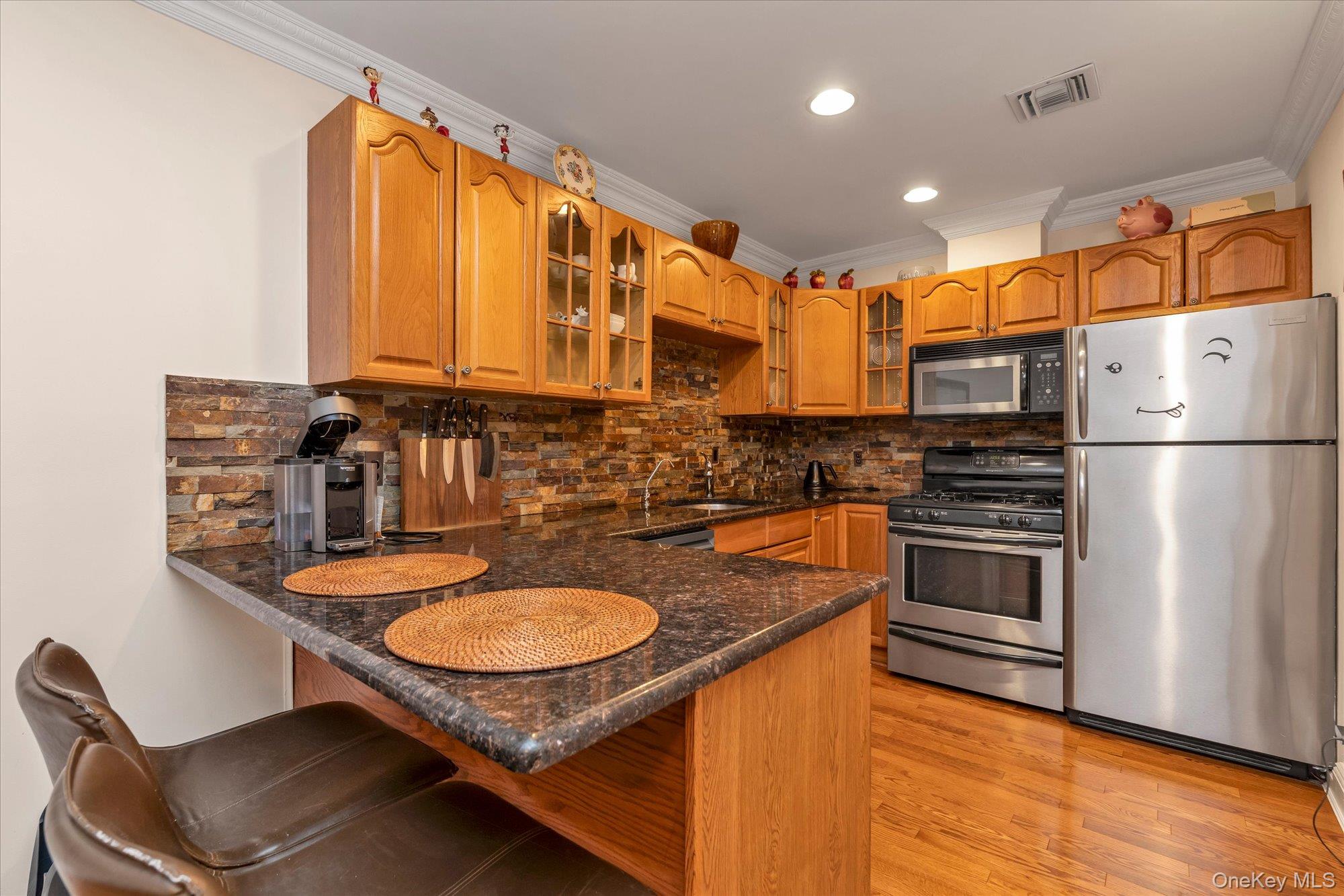 150 I U Willets Road Albertson, NY 11507 - Photo 10 of 21 Kitchen featuring wood cabinetry, stainless steel appliances, and wood-finish flooring