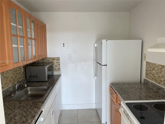 a kitchen with granite countertop a refrigerator and a sink