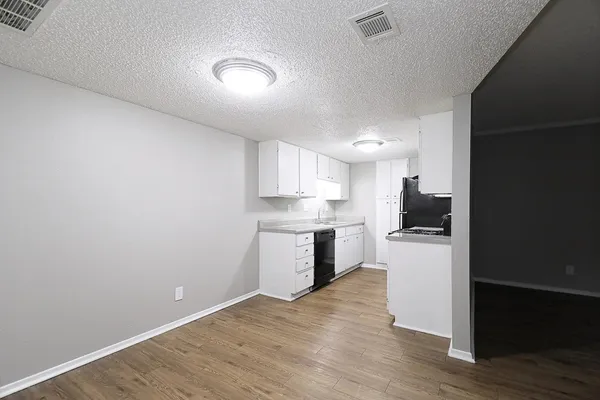 a kitchen with a refrigerator a stove top oven and white walls