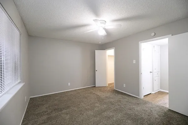 an empty room with chandelier fan and windows