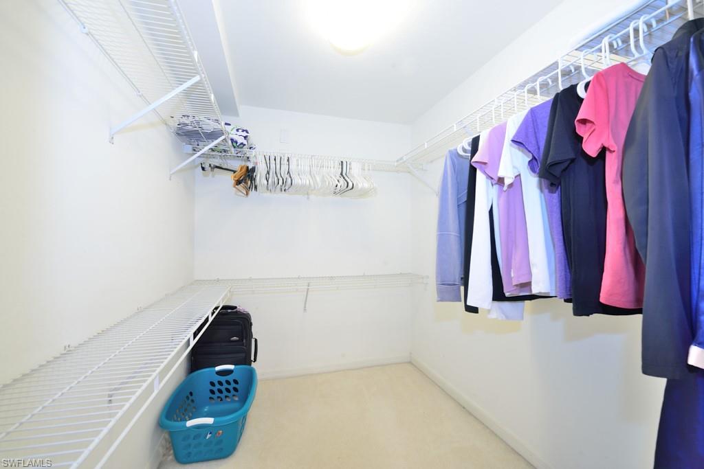 4960 Deerfield Way, Unit E102 Naples, FL 34110 - Photo 14 of 19 a view of walk in closet with clothes and shoes