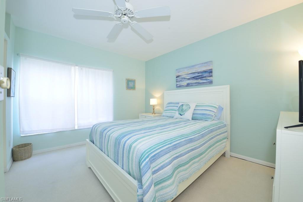 4960 Deerfield Way, Unit E102 Naples, FL 34110 - Photo 15 of 19 a bedroom with a bed and a chandelier