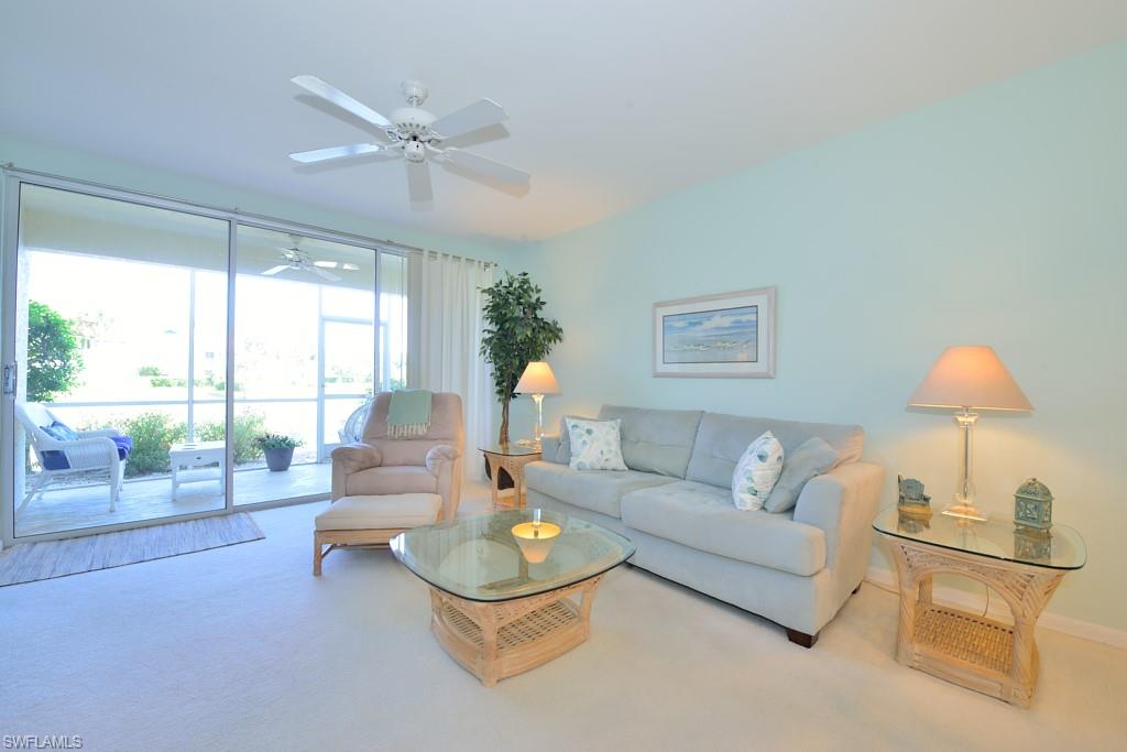 4960 Deerfield Way, Unit E102 Naples, FL 34110 - Photo 4 of 19 a living room with furniture and a large window with balcony view