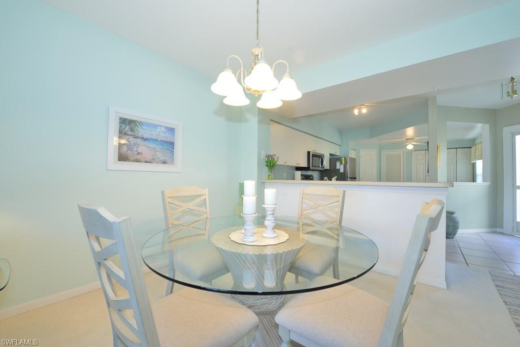 4960 Deerfield Way, Unit E102 Naples, FL 34110 - Photo 7 of 19 a dining room with furniture and a chandelier