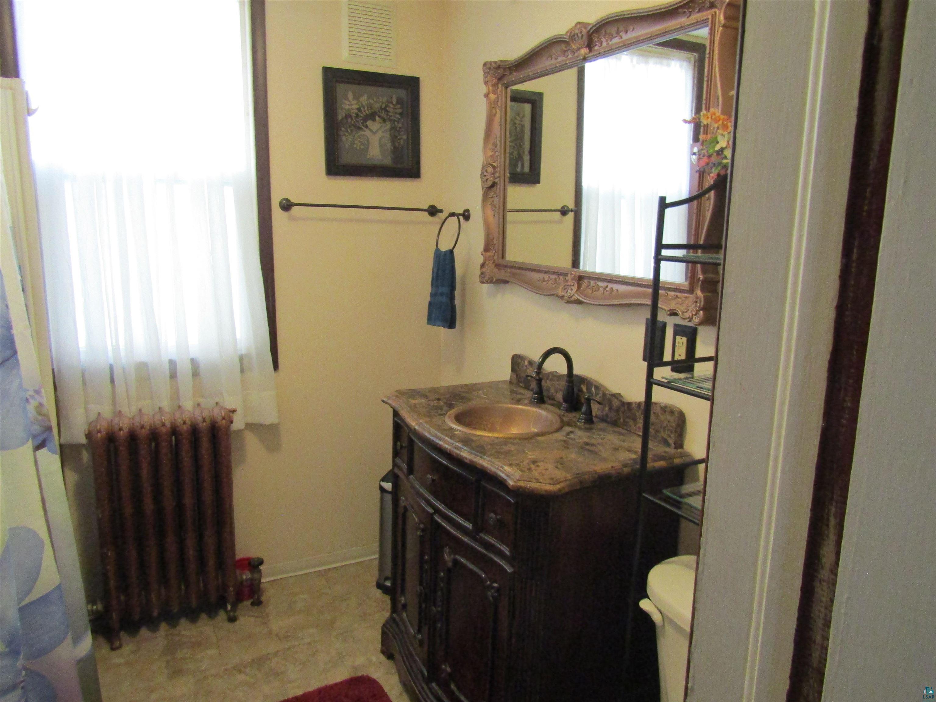 1115 Harrison Street Superior, WI 54880 - Photo 18 of 49 Bathroom featuring a decorative wood-finish vanity with a stone countertop and an undermount copper-tone sink