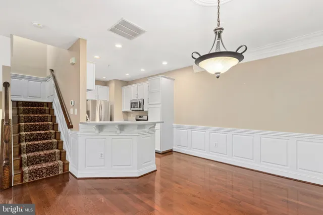 a kitchen with stainless steel appliances granite countertop a refrigerator a stove a sink dishwasher and white cabinets with wooden floor