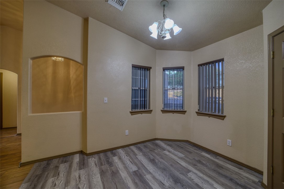 2213 Jamie Road Fort Mohave, AZ 86426 - Photo 12 of 51 Empty room with wood finished floors, a chandelier, and a textured wall