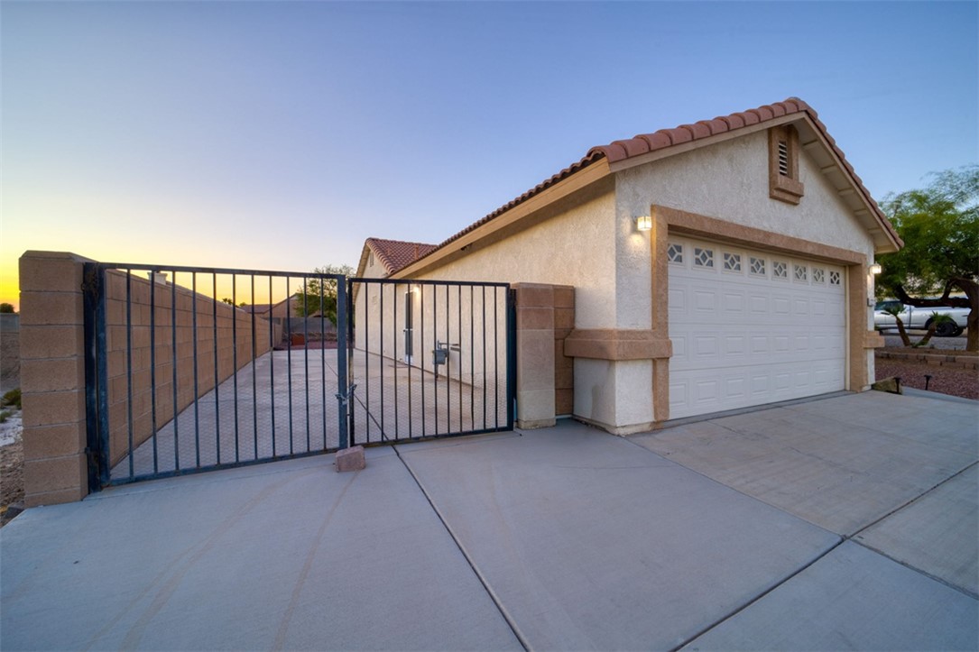 2213 Jamie Road Fort Mohave, AZ 86426 - Photo 2 of 51 View of home's exterior with a gate, stucco siding, driveway, and a tiled roof